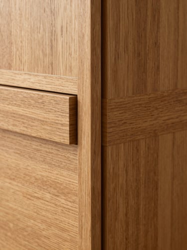 Macro detail of a grain-matched timber veneer wardrobe corner joint, flush-aligned, recessed handle, warm oak tones, sharp focus
