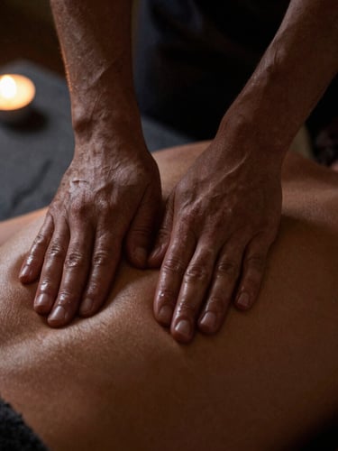 Close-up of hands performing precise massage techniques on a back, dimly lit with warm amber light, shallow depth of field, dark slate background.