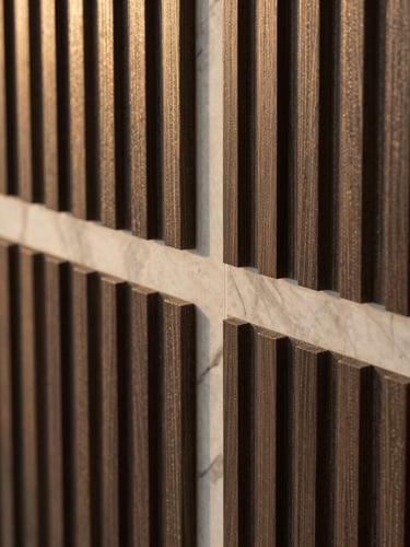 Close-up detail shot of premium fluted WPC panels and marble slab seams, dramatic side lighting highlighting the rich textures and precise joints, warm editorial photography style.