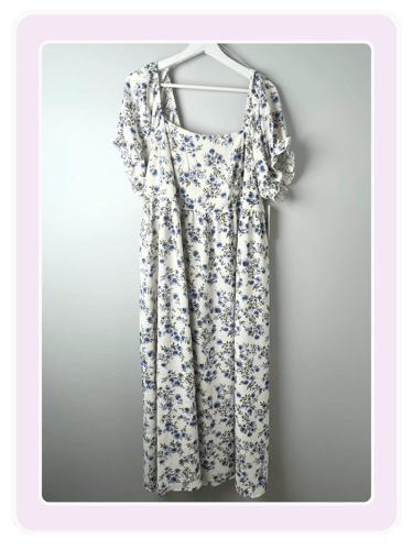White midi dress with a blue floral pattern and ruffled short sleeves on a white hanger.