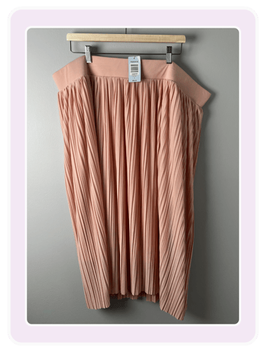 Torrid rose gold pleated midi skirt with an elastic waistband hanging on a wooden clip hanger.