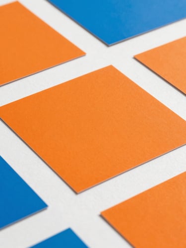 Extreme close-up of vibrant orange and electric blue color swatches lying on a pristine white drafting table, sharp graphic shadows, 35mm