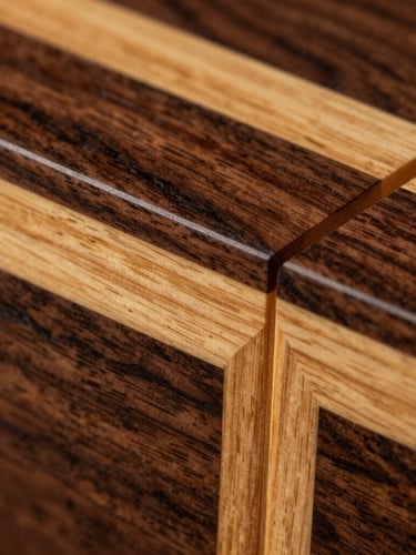 Extreme macro close-up of a marquetry joint, showing the flawless connection between dark walnut and golden sycamore veneer, dramatic chiaroscuro lighting emphasizing the fine wood grain
