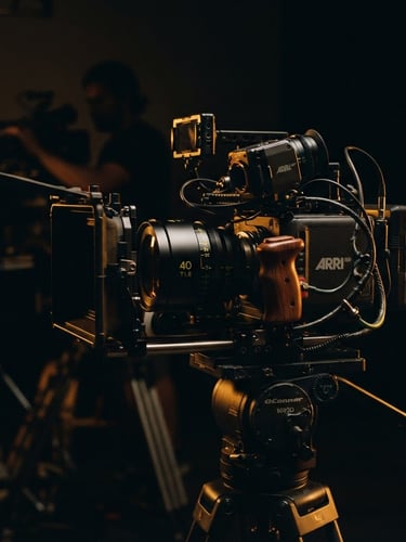 Cinematic close-up of a high-end camera rig on a dark corporate set, dramatic low-key lighting with deep shadows and warm amber backlighting, anamorphic lens, 35mm film look