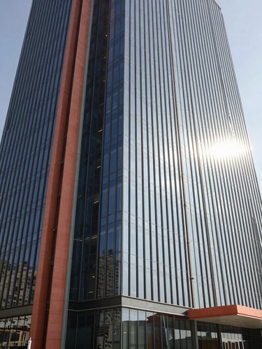 A wide-angle architectural shot of a modern corporate headquarters in Jeddah, sleek glass facade reflecting bright morning Saudi sunlight, clean lines, professional atmosphere.