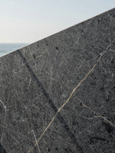 Extreme close-up of high-quality dark grey marble texture with subtle golden veins, structured geometric shadows, minimalist editorial feel