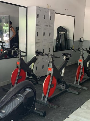 A modern gym interior featuring stationary bikes, elliptical machines, and storage lockers for fitness training.