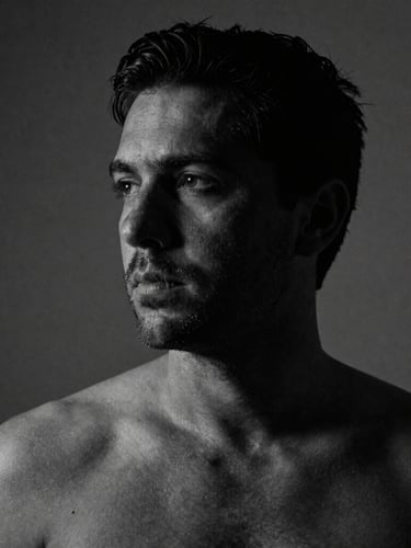 Black and white portrait of director Daniel Sanabria, dramatic low-key lighting, deep shadows, raw skin texture, 35mm anamorphic lens, looking off-camera.