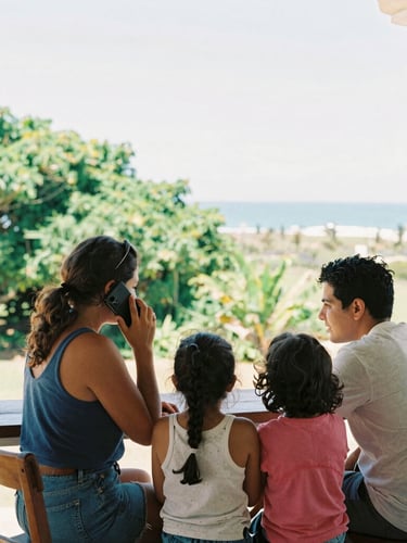 Warm editorial photography of a local family in Arenillas sharing a phone call on a sunlit veranda, lush green coastal foliage in the background, candid moment, 35mm film style.