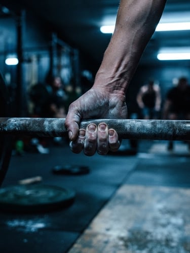 Dynamic close-up of chalked hands gripping a heavy barbell in a moody gym with cool blue highlights, raw and authentic 35mm film style.