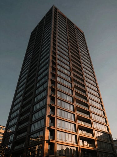 Low-angle architectural power shot of a modern luxury residential tower facade in Istanbul, dramatic twilight lighting, bronze and glass details, cinematic.