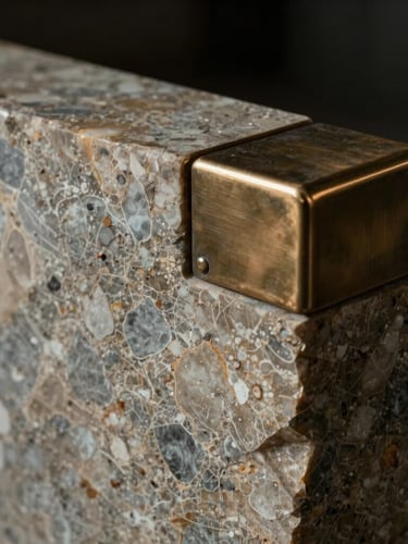 Close-up of raw travertine marble block paired with brushed bronze accents, dramatic side lighting, dark moody atmosphere.