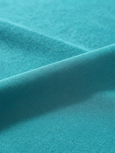 Close-up macro shot of teal cold spandex viscose fabric texture, showing the fine breathable weave, soft folds, clean studio lighting