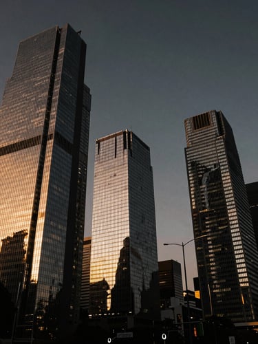 Cinematic wide-angle shot of Paseo de la Reforma skyscrapers in Mexico City at twilight, dramatic golden hour reflections on glass facades, high-contrast low-key lighting, deep obsidian and champagne gold tones