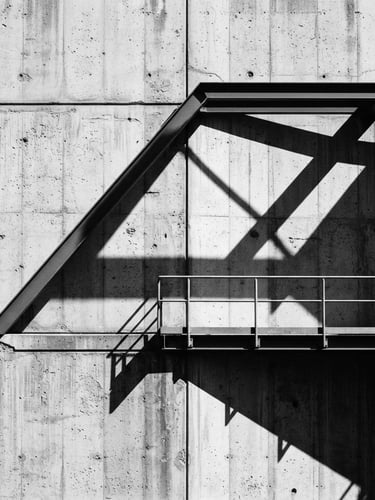 Minimalist architectural photography of a raw concrete wall with sharp geometric shadows, natural light, high contrast, 35mm