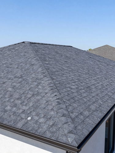 Clean wide-angle architectural shot of a newly installed asphalt shingle roof on a modern suburban home, bright sunny daylight, sharp focus, 35mm.