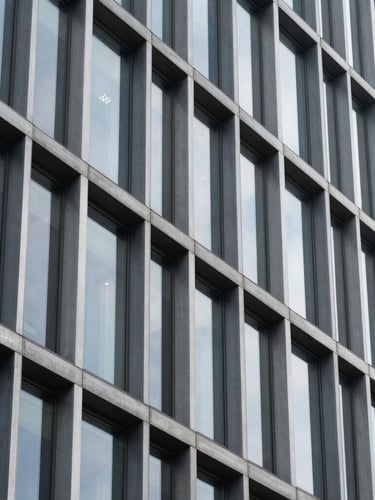 A close-up architectural crop of a modern steel and glass building facade, clean geometric lines, crisp daylight