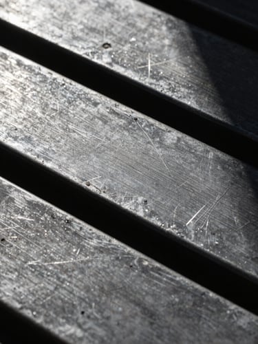Macro close-up of raw, scratched metal plates under harsh direct flash, dramatic deep shadows, brutalist texture.
