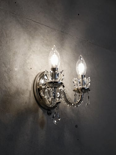 Tight studio shot of a pair of crystal wall sconces mounted on a bare concrete wall, cool directional strobes catching cut crystal arms, deep shadow behind each piece, no room context visible