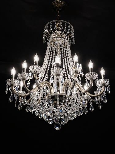 Studio overhead view of a large multi-tier crystal chandelier suspended against a seamless black background, cool strobe light fracturing through hundreds of cut facets, extreme contrast, no floor