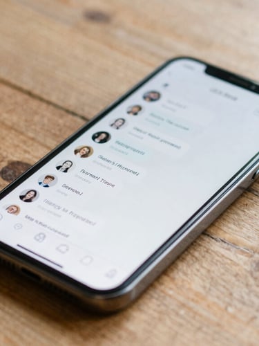 A real, unpolished close-up of a smartphone displaying a clean chat interface with local neighborhood messages, resting on a rustic wooden table in natural daylight.