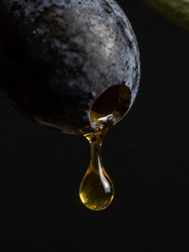 Macro shot of a single golden olive oil droplet falling from a black olive, dramatic chiaroscuro lighting, deep black background, ultra-high-detail 8k