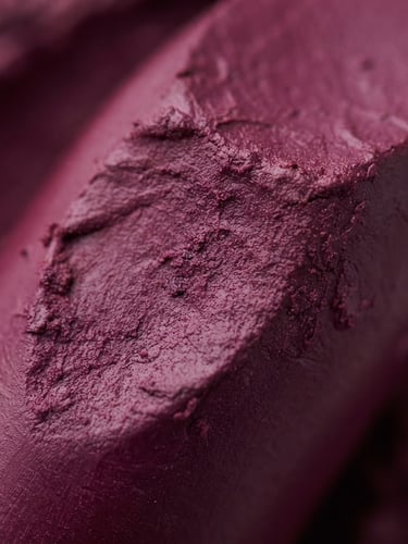 Macro studio shot of rich, velvety plum-colored lipstick cream texture, high-key lighting, soft shadows, professional editorial depth of field.