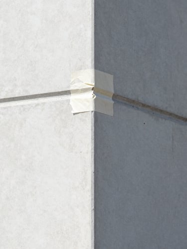 Sharp architectural photography of a perfectly taped paint edge on a clean concrete wall, bright daylight, high contrast, crisp details, 35mm lens.