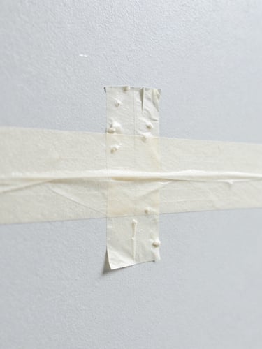 Macro shot of a clean paint line being taped off on a smooth wall, sharp focus, bright daylight, high-contrast cool tones