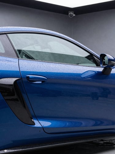 Side profile of a luxury sports car with high-contrast studio reflections, showing water beading on the hydrophobic ceramic coating