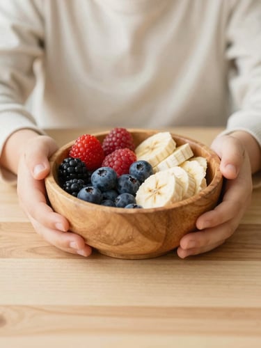 Close-up of a child's hands holding a wooden bowl filled with fresh colorful berries and sliced bananas on a light wooden table, soft natural daylight, warm Scandinavian style