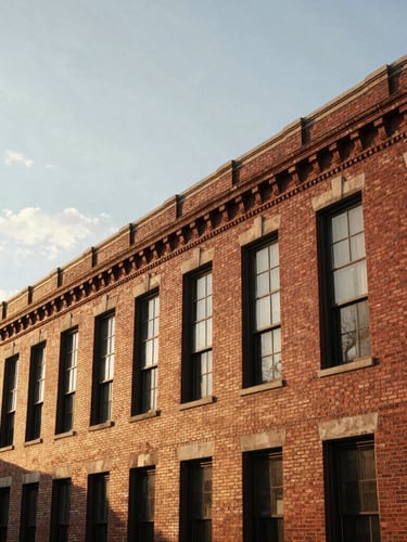 Wide environmental shot of a historic brick building in Midtown St. Louis during warm golden hour, natural overcast daylight reflecting off masonry, architectural detail, negative space on the left.