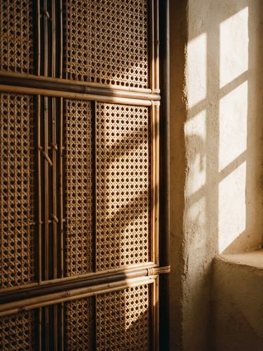 Architectural close-up of a folding rattan screen in a sunlit room, strong directional afternoon light casting soft-edged shadows on a warm plaster wall, 35mm.