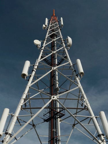 Wide-angle environmental shot of a massive telecommunication tower rising into a dramatic, high-contrast cool sky, sharp architectural details