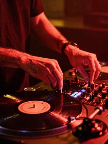 Close-up of professional DJ hands adjusting a gold-accented mixer knob, vinyl spinning on a turntable, low light, warm crimson glow, high contrast