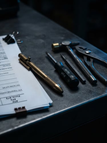Macro close-up of a clean dark desk with FFL paperwork, a brass pen, and assembly tools under moody side-lighting, deep blue rim highlights.