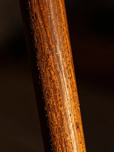 Extreme close-up of aged hand-carved wooden Yoruba ancestral staff, showing deep wood grain and chisel marks, side-lit with warm golden light, dark background, 35mm