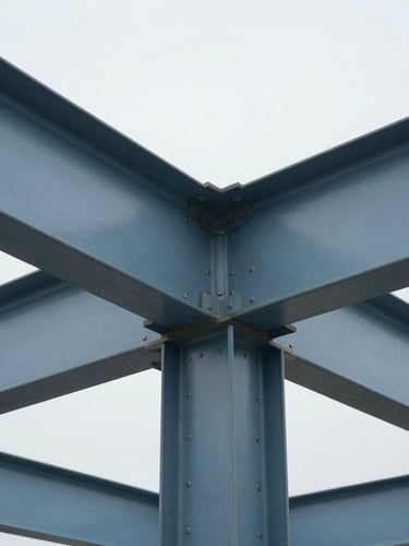 Tight technical detail shot of structural steel joints in a clean modern building interior, crisp daylight, cool overcast tones, high clarity