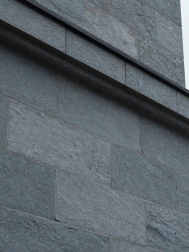 Close-up architectural detail of a Swiss stone facade with precise geometric lines, soft overcast daylight, cool slate gray tones, minimal and structured, 35mm lens