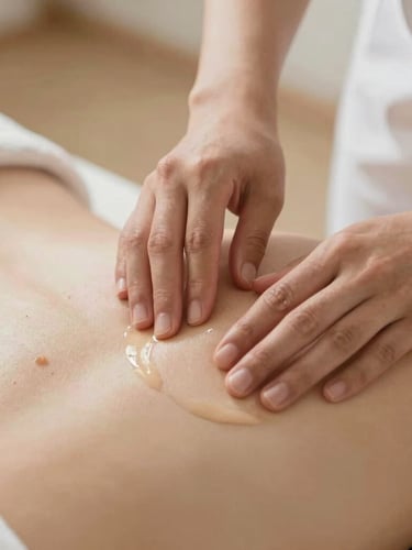 Close-up of therapist hands gently applying organic oil to a back, soft diffused natural daylight, warm sand tones, shallow depth of field, 35mm