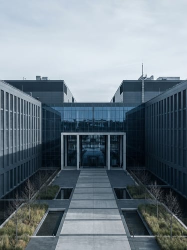 Wide architectural view of a modern data center with clean geometric lines, cool diffused daylight, sharp shadows, symmetrical composition, desaturated slate and deep blue tones.