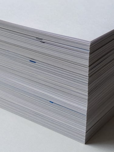 A clean vertical stack of perfect-bound corporate catalogs showing crisp spine alignment and heavy paper textures under sharp, cool studio lighting.