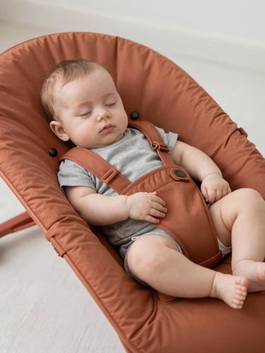 Hands carefully steaming a soft fabric baby bouncer with a professional steamer, warm natural light, clean and pure atmosphere, 35mm