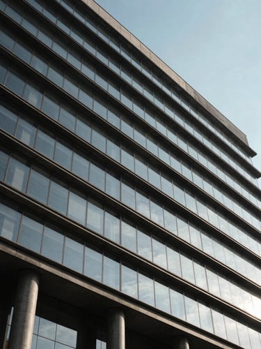 Architectural low-angle shot of a modern government office building facade in Mexico, clean glass and dark concrete lines, dramatic shadows under a clear sky.