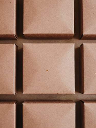 Overhead flat-lay of structured saffron gift boxes with clean gold foil-stamping, soft diffused natural side-light, warm desaturated clay tones, 35mm film.