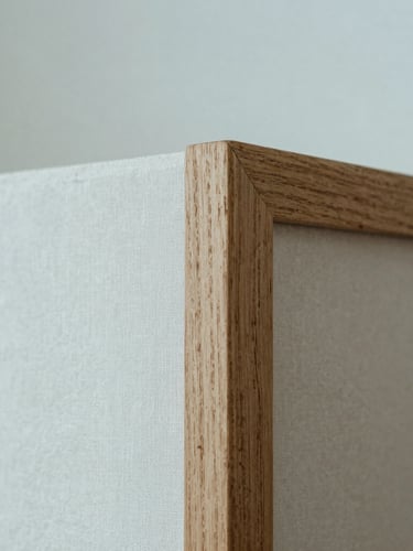 A minimalist macro photograph of a perfectly joined natural oak frame corner, soft diffused daylight, shallow depth of field, linen mat texture visible.