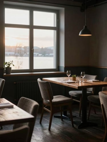 Wide environmental shot of a moody Scandinavian restaurant dining room at sunrise, low-key directional natural light streaming through a large window, rustic wooden tables, empty linen-draped chairs, soft shadows.