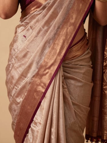 Close-up of a premium silk saree drape in rose gold and deep burgundy, soft studio lighting, editorial fashion photography