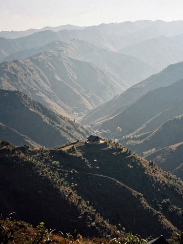 Wide panoramic landscape of misty northern Vietnamese mountains, Ha Giang region, deep valleys, a single tiny traditional house on a ridge showing scale, high-contrast natural morning light, deep shadows, 35mm film grain, cinematic editorial style.