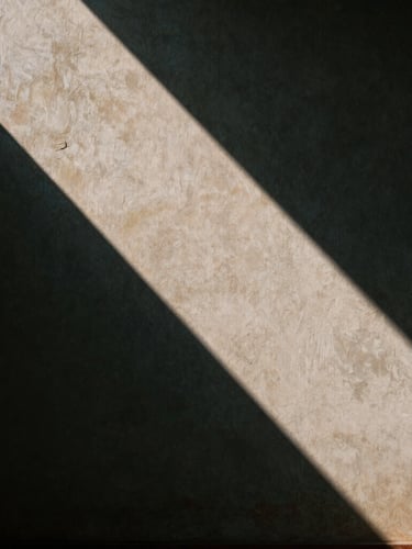 Minimalist architectural geometry of an ancient temple wall in Hue, strong diagonal shadows, high contrast light, textured plaster, cinematic 35mm
